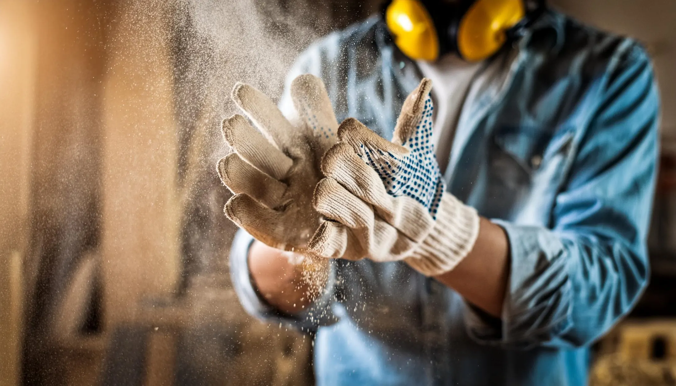 Handwerker klopft Staub aus den Arbeitshandschuhen